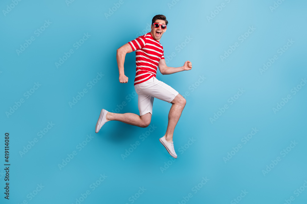 Full length body side profile photo happy man jumping high running fast isolated on vibrant blue color background
