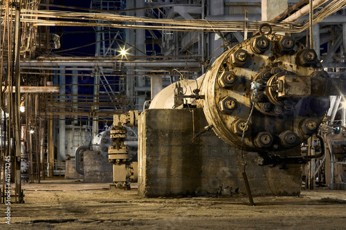 Petrochemical plant exterior huge high pressure centrifugal circulation compressor for gas compression with current drive on concrete base. Selective focus night view industrial background.