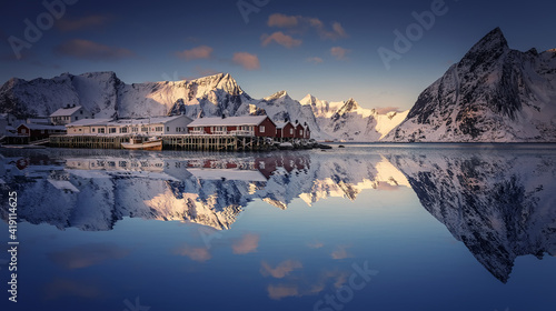 Scenic image of Norway nature in winter sunny day. Snowcapped mountains, perfect sky, red rorbues with reflected in water. Impressively beautiful Scenery of Lofoten islands. Beauty of nature concept