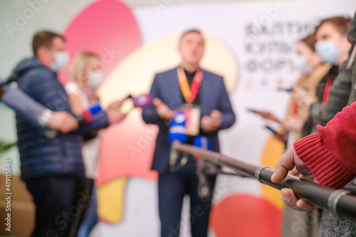 Anonymous reporter holding microphone near speaker © Anton Gvozdikov