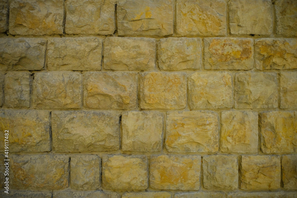 Fototapeta premium Modern yellow stone brick wall background close-up. Copy space. Natural. Building exterior 
