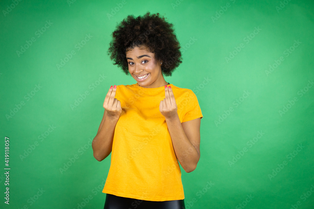 African american woman wearing orange casual shirt over green background doing money gesture with hands, asking for salary payment, millionaire business African american woman wearing orange casual shirt over green background doing money gesture with hands, asking for salary payment, millionaire business