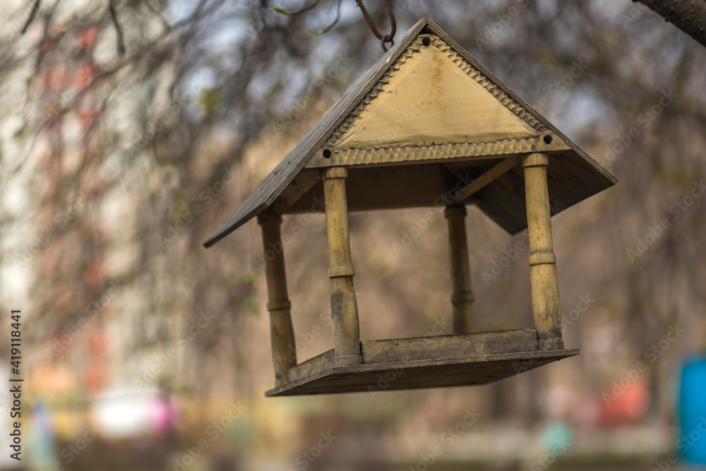 Spring landscape-bird feeder in the form of a house hanging on a tree against the background of early spring. Feeder. Early spring day on garden. Spring landscape-bird feeder in the form of a house hanging on a tree against the background of early spring. Feeder. Early spring day on garden.