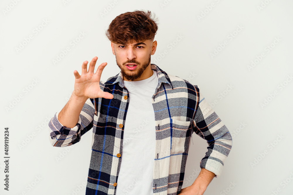 Young Moroccan man isolated on white background showing claws imitating a cat, aggressive gesture. Young Moroccan man isolated on white background showing claws imitating a cat, aggressive gesture.