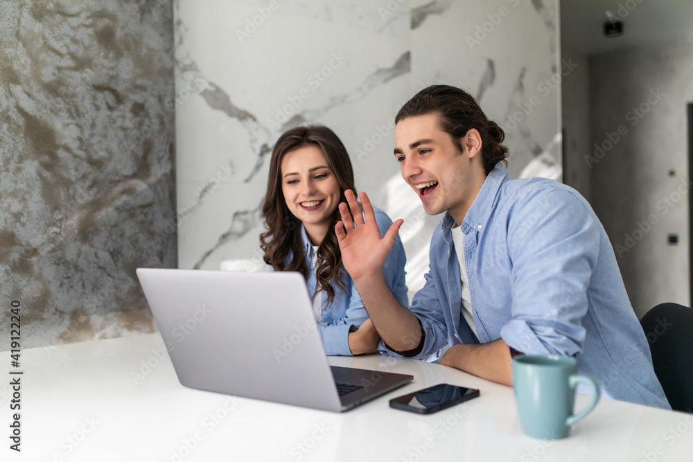 Video call. Nice pleasant couple sitting in front of the laptop while calling to their relatives Video call. Nice pleasant couple sitting in front of the laptop while calling to their relatives