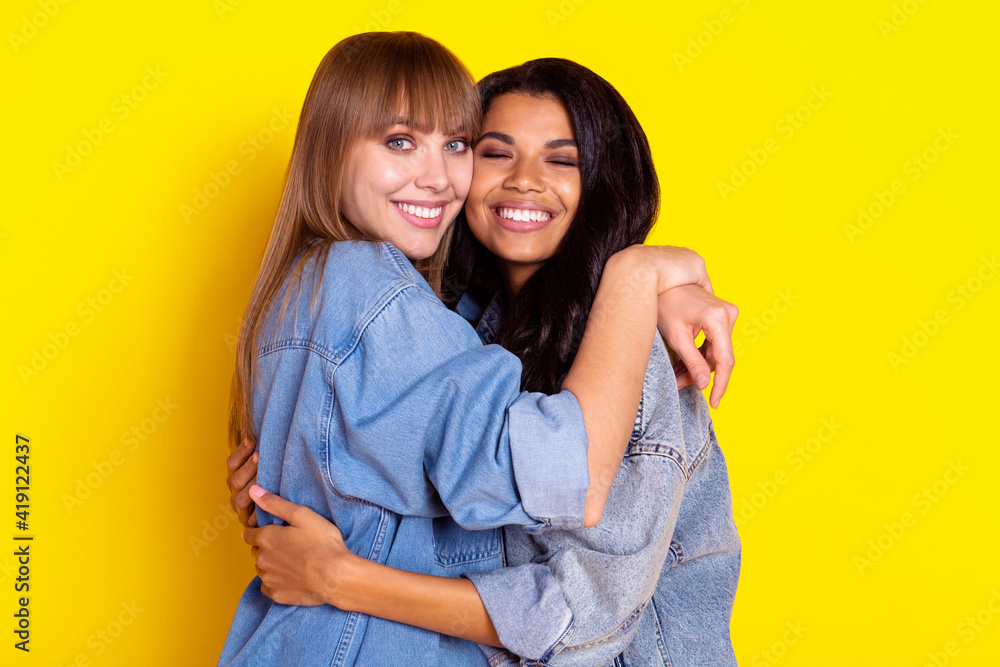 Profile photo of pretty cheerful ladies diversity hugging have good mood isolated on yellow color background Profile photo of pretty cheerful ladies diversity hugging have good mood isolated on yellow color background