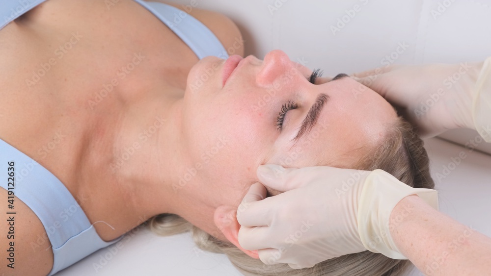 Facial massage beauty treatment. Close up of a young womans face lying on back, getting face lifting massage, pinch and roll technique Facial massage beauty treatment. Close up of a young womans face lying on back, getting face lifting massage, pinch and roll technique