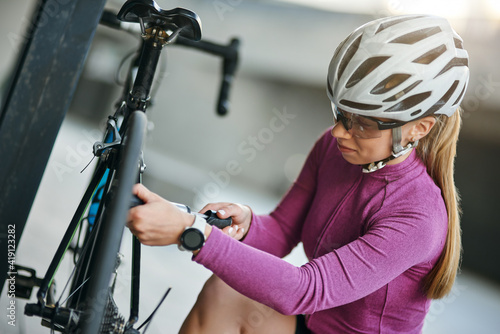 фотографія Concentrated female cyclist wearing protective helmet and glasses looking focuse