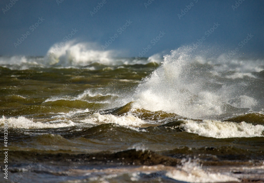 Storm clouds above the Baltic sea in winter. Dramatic sky, waves and water splashes. Dark seascape. Latvia.