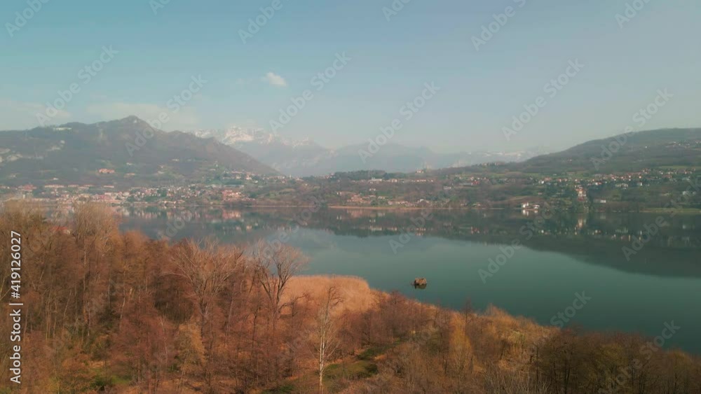 Beautiful Landscape View Of Idyllic Lake With Mountains In Background In Annone Lake, Northern Italy - aerial drone ascending Beautiful Landscape View Of Idyllic Lake With Mountains In Background In Annone Lake, Northern Italy - aerial drone ascending