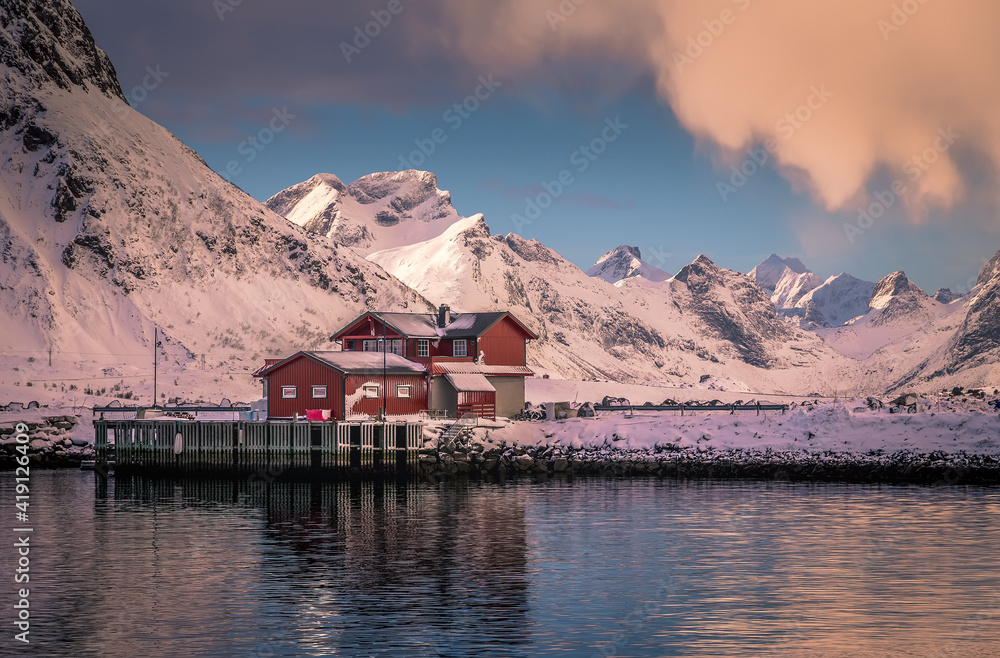 Amazing nature scenery. Winter landscape during sunrise. winter mountains and fjord with typical rorbu and fishing boats on calm water. Lofoten islands. North Norway. Scenic image scandinavian nature.