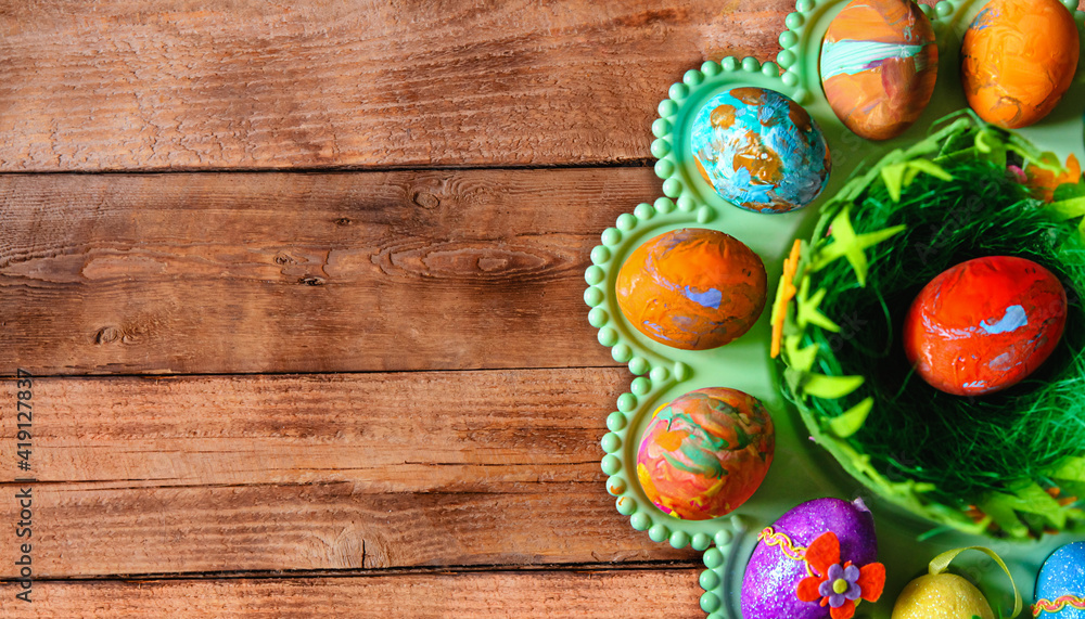 Colorful Easter eggs painted in gouache on a green stand on a wooden table. Top view. Space for text Colorful Easter eggs painted in gouache on a green stand on a wooden table. Top view. Space for text