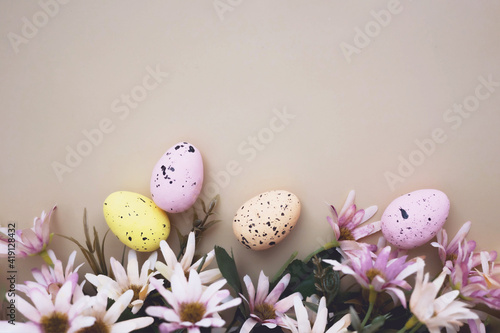 Colorful easter eggs flowers on pastel background with copy space. Flat lay.