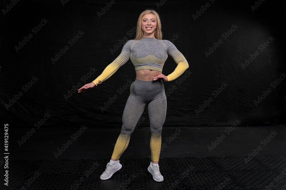smiling sportswoman posing against a dark background. fitness clothing. healthy lifestyle concept