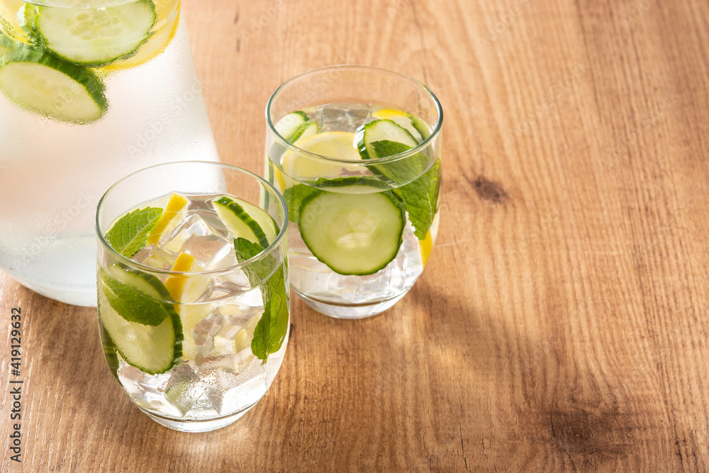 Sassy water or water with cucumber and lemon on wooden table. Copy space Sassy water or water with cucumber and lemon on wooden table. Copy space