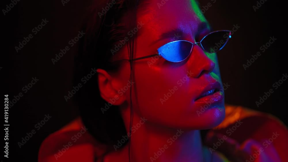 Pretty girl slow motion moving in neon light on black background. Beautiful girl dancing in lights wearing sunglasses. Art design of female disco dancing, Night club, Party. FHD footage. Pretty girl slow motion moving in neon light on black background. Beautiful girl dancing in lights wearing sunglasses. Art design of female disco dancing, Night club, Party. FHD footage.