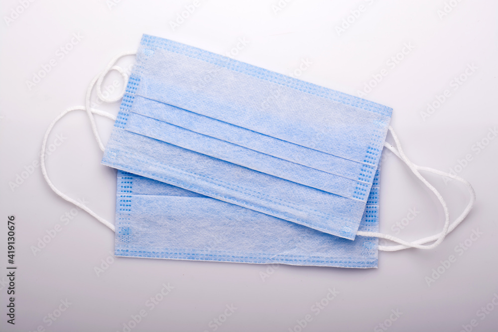 Medical mask, medical protective mask isolated on blue background. The disposable surgical face mask covers the mouth and nose. Medical mask, medical protective mask isolated on blue background. The disposable surgical face mask covers the mouth and nose.