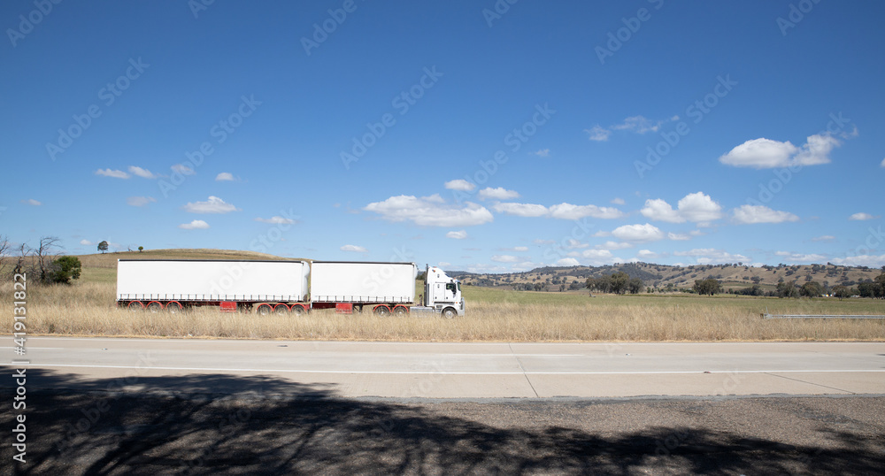Truck on a freeway in an Australian Country Town midway between Sydney and Melbourne with nice blue sky and lush green trees as a backdrop