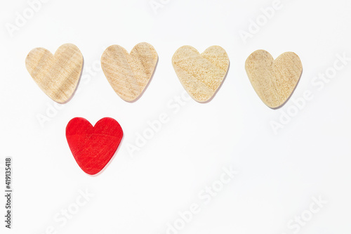 four wooden hearts, one red heart. isolated on white background. concept of unique feelings
