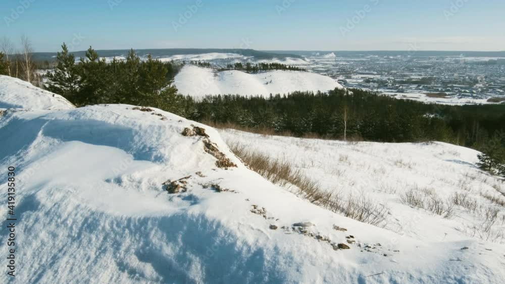 The camera looks at an industrial and working city, and then slowly descends and moves through a snow-covered clearing in a winter forest above the snow. The snow glistens. The camera looks at an industrial and working city, and then slowly descends and moves through a snow-covered clearing in a winter forest above the snow. The snow glistens.