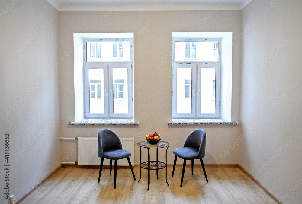 Fototapeta premium Modern interior design concept. Minimalistic style. Two blue armchairs and a table with fruit.