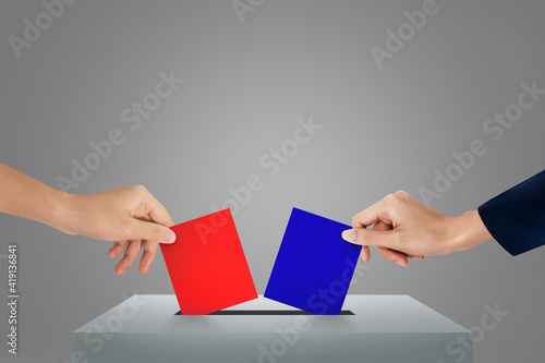 Hands holding red and blue ballot paper for election vote concept.