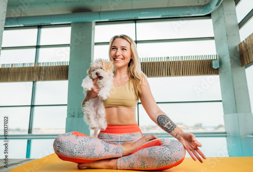 Smiling girl with a small white dog near the pool 