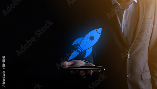 Start up concept with businessman holding abstract digital rocket icon rocket is launching and soar flying