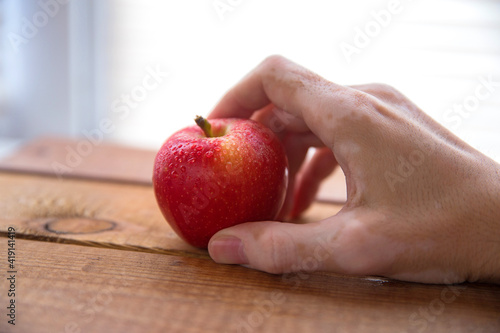 Wallpaper Mural vitiligo hand holds a red apple in the palm of your hand and presses it with your finger Torontodigital.ca
