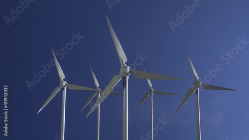 Row of wind power generators on blue sky background. 3d illustration © Dmitry