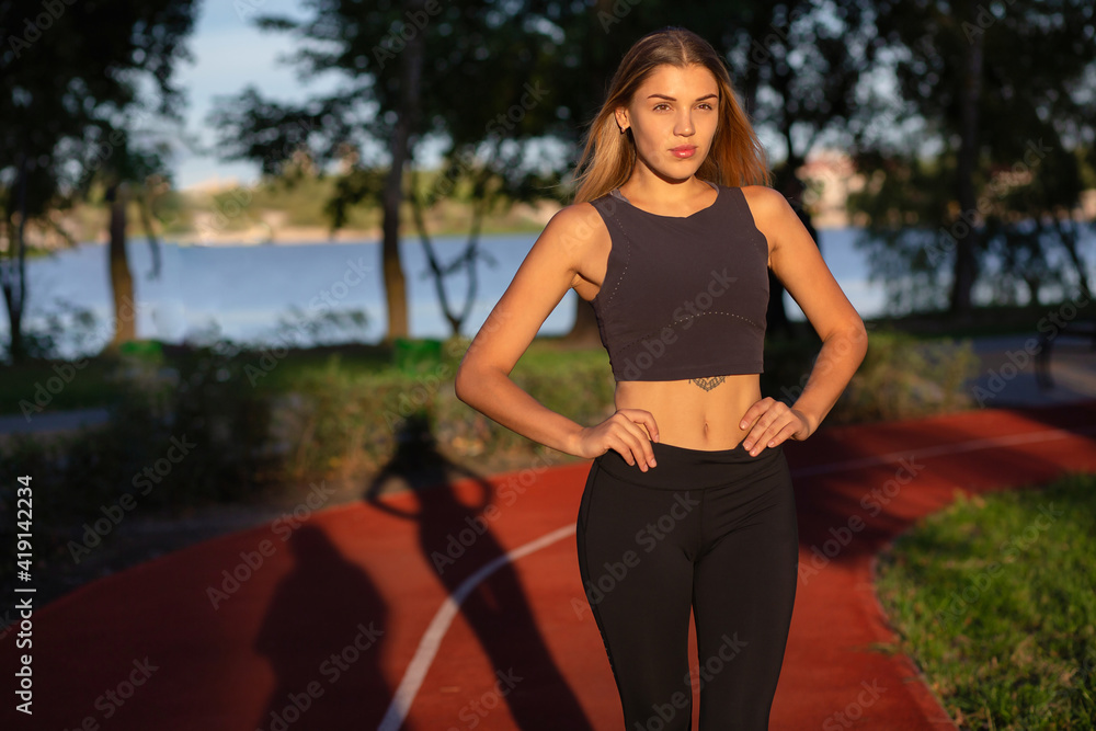 Splendid blond lady with sporty figure posing at the park