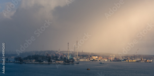 Stockholm's islands with amusement park, which is located on coastal side.Unique moment with mixed weather conditions wheres sunshine meets snow storm and creates game of light. Picture with haze. © Zdena Venclik