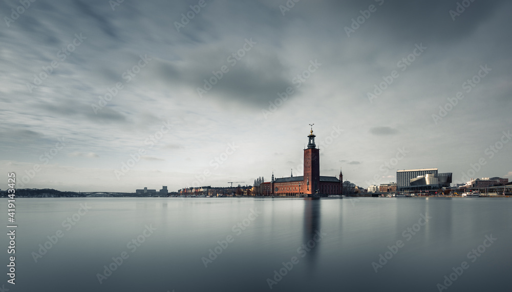 Long exposure of a minimalist view of the capital of Sweden-Stockholm. In the middle of the picture is an iconic building-City Hall, which is reflected in the lake. The clouds are moving in the sky.