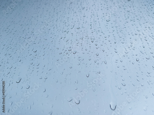 Raindrops on a window pane close-up. Abstract blue background.