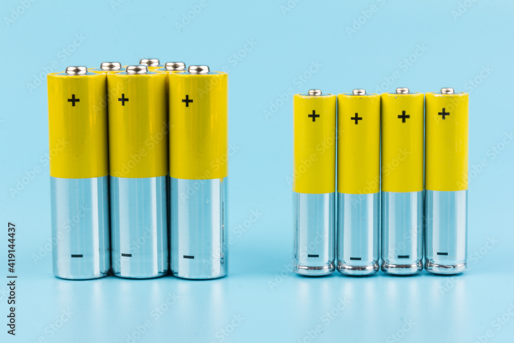Photo of gray-yellow alkaline AA batteries on blue background. Recycling of rechargeable NiMH batteries. The most popular size of accumulators. Copy space. Photo of gray-yellow alkaline AA batteries on blue background. Recycling of rechargeable NiMH batteries. The most popular size of accumulators. Copy space.
