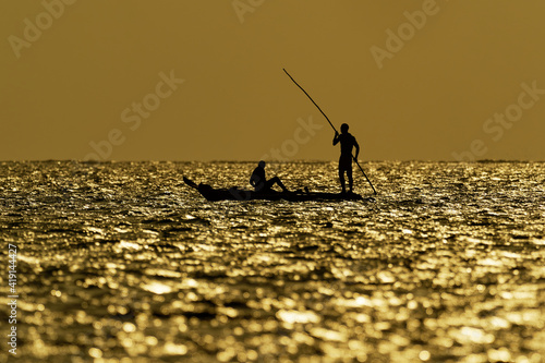 Zanzibar Island coast (Tanzania, Zanzibar Archipelago). Typical local aboriginal boats in the evenind and the dusk. Ocean with the sailing boat. Sunrise or sunset, silhouette and outline photo