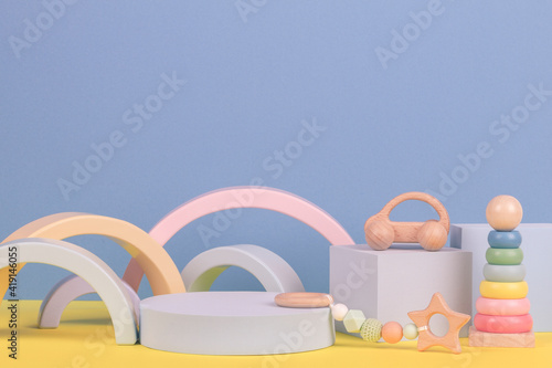 Babby kid toy background. Composition of colorful educational toys and geometric shapes podium, platform on blue and yellow background © vejaa