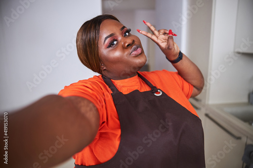 Quadro em tela Pretty lady in apron posing for selfie with pout lips