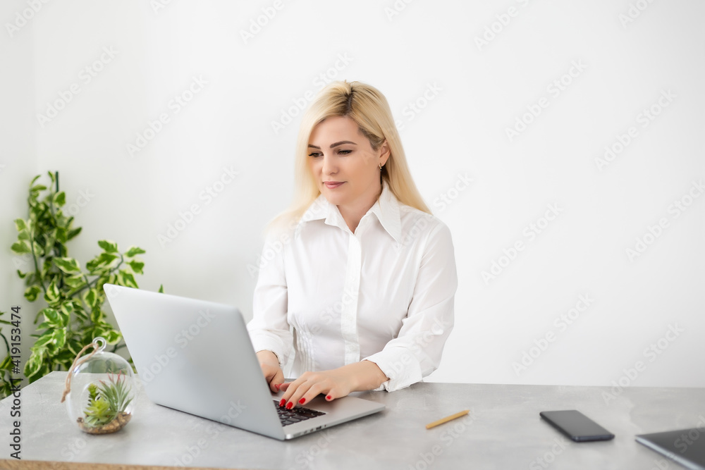 Happy Young Beautiful Woman Using Laptop, Indoors on white wall background Happy Young Beautiful Woman Using Laptop, Indoors on white wall background