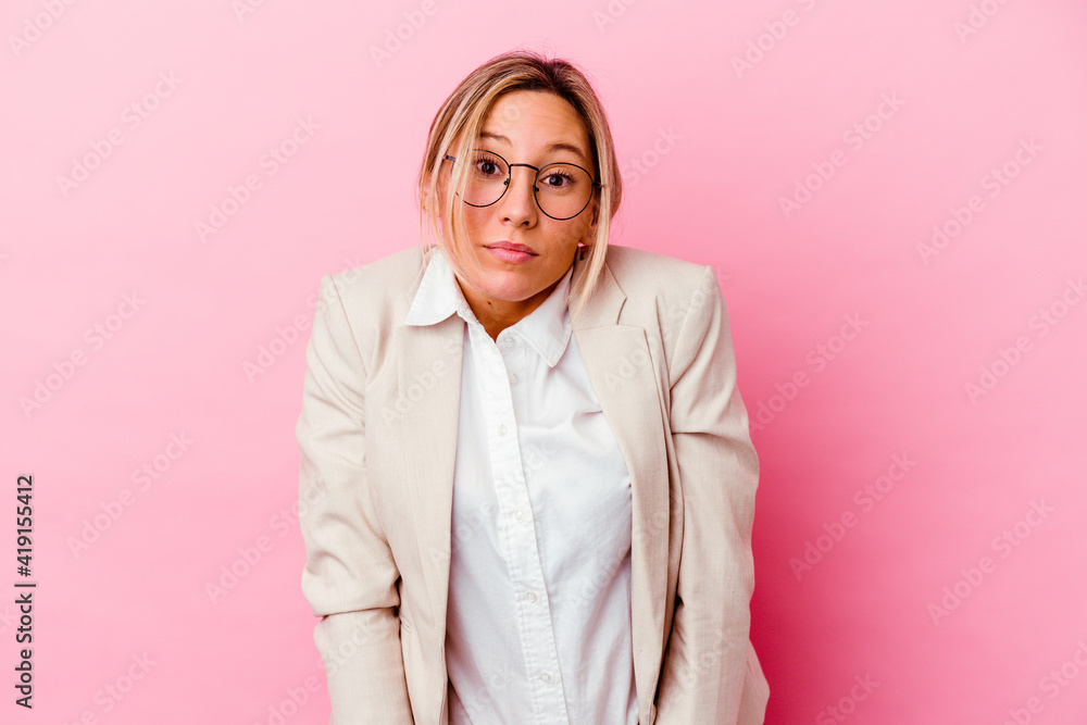 Young caucasian mixed race business woman isolated on pink background shrugs shoulders and open eyes confused. Young caucasian mixed race business woman isolated on pink background shrugs shoulders and open eyes confused.