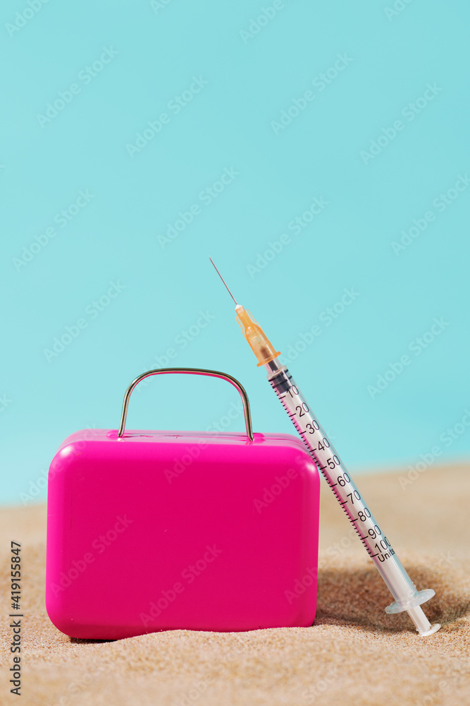 Fototapeta premium suitcase and syringe on the sand