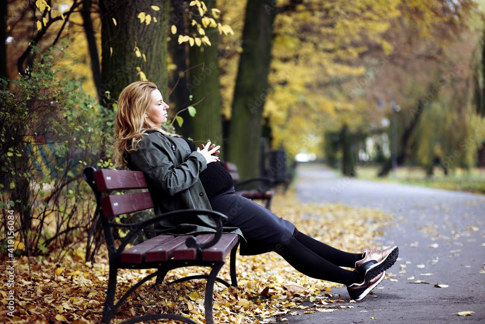 Blond woman sitting on park bench in autumn, Piotrkow Trybunalski, Poland Blond woman sitting on park bench in autumn, Piotrkow Trybunalski, Poland