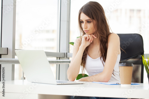 Beautiful businesswoman working on laptop in bright modern office