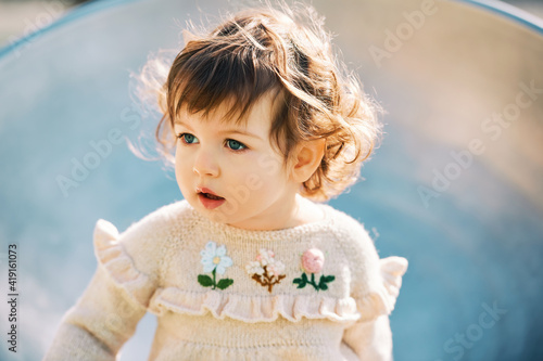 Outdoor close up portrait of adorable toddler girl having fun on playground  1 - 2 year old kid playing in park