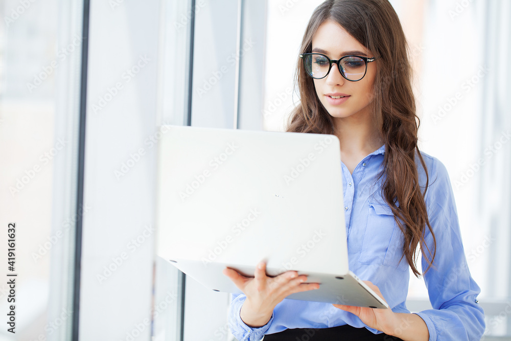 Young confident businesswoman working at office desk and typing with a laptop Young confident businesswoman working at office desk and typing with a laptop