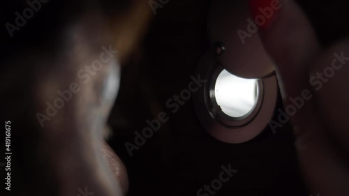 close-up of worried woman looking through the peephole in theevening, eye photo