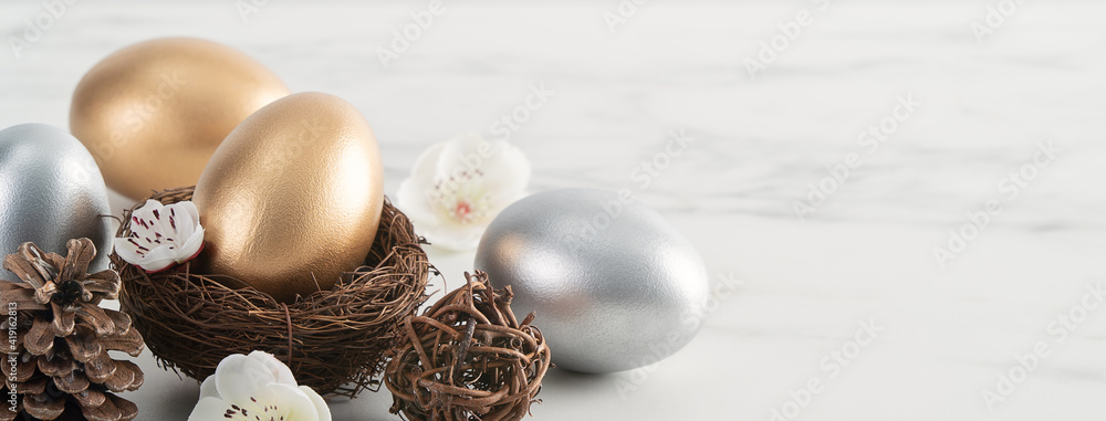 Obraz premium Close up of golden and silver Easter eggs in the nest with white plum flower.