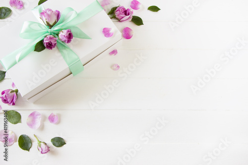 Gift box with bow and pink roses, leaves and petals, empty space , white background. Template for Mother's day, 8 march, birthday, women's day, wedding, Valentine's day