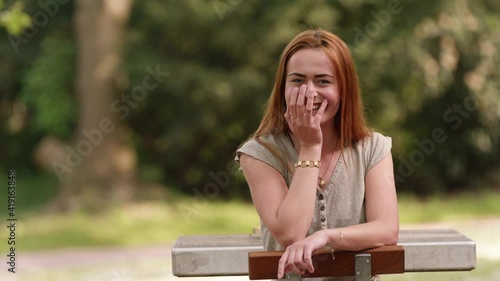 [4k] cute young redhead giggling at table in public park