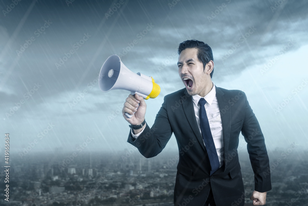 Asian businessman shouting something on the megaphone Asian businessman shouting something on the megaphone